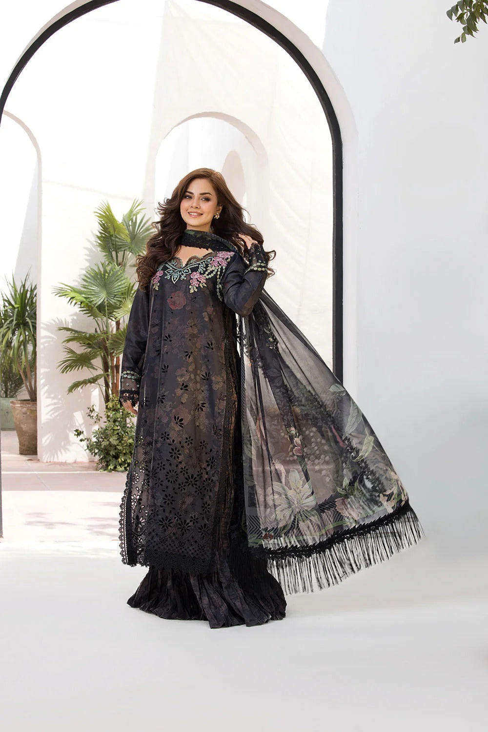 Woman in a black embroidered dress with a matching scarf against a white background