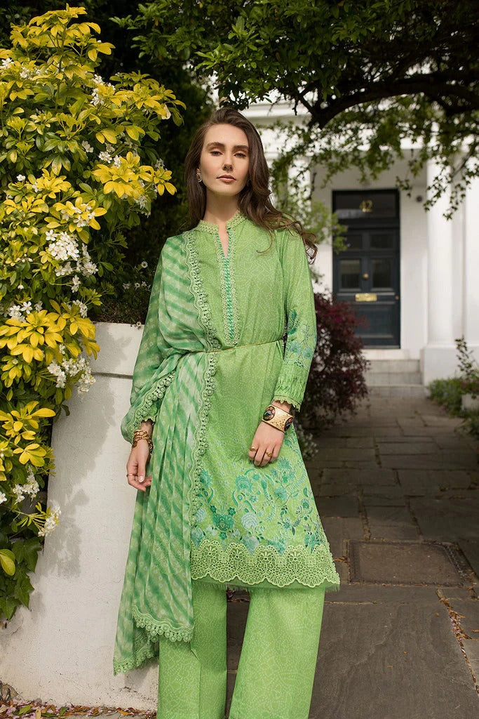 A woman modeling a light green three-piece traditional outfit with matching trousers and a draped scarf, standing outdoors in front of a white building with green foliage.