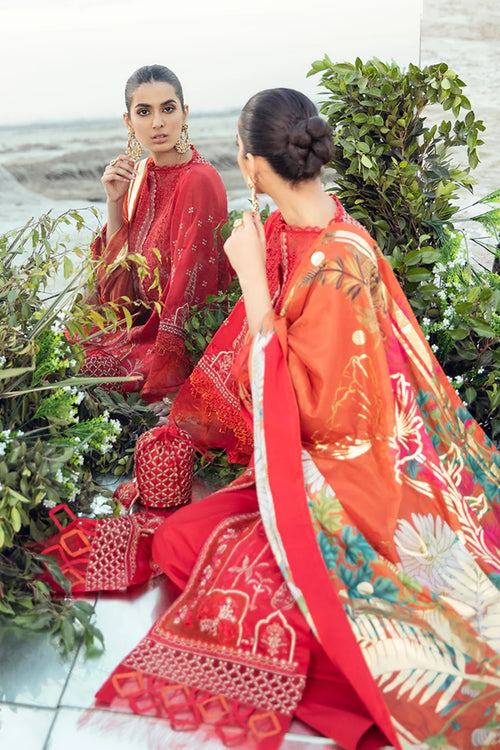Woman in a red traditional outfit sitting among greenery