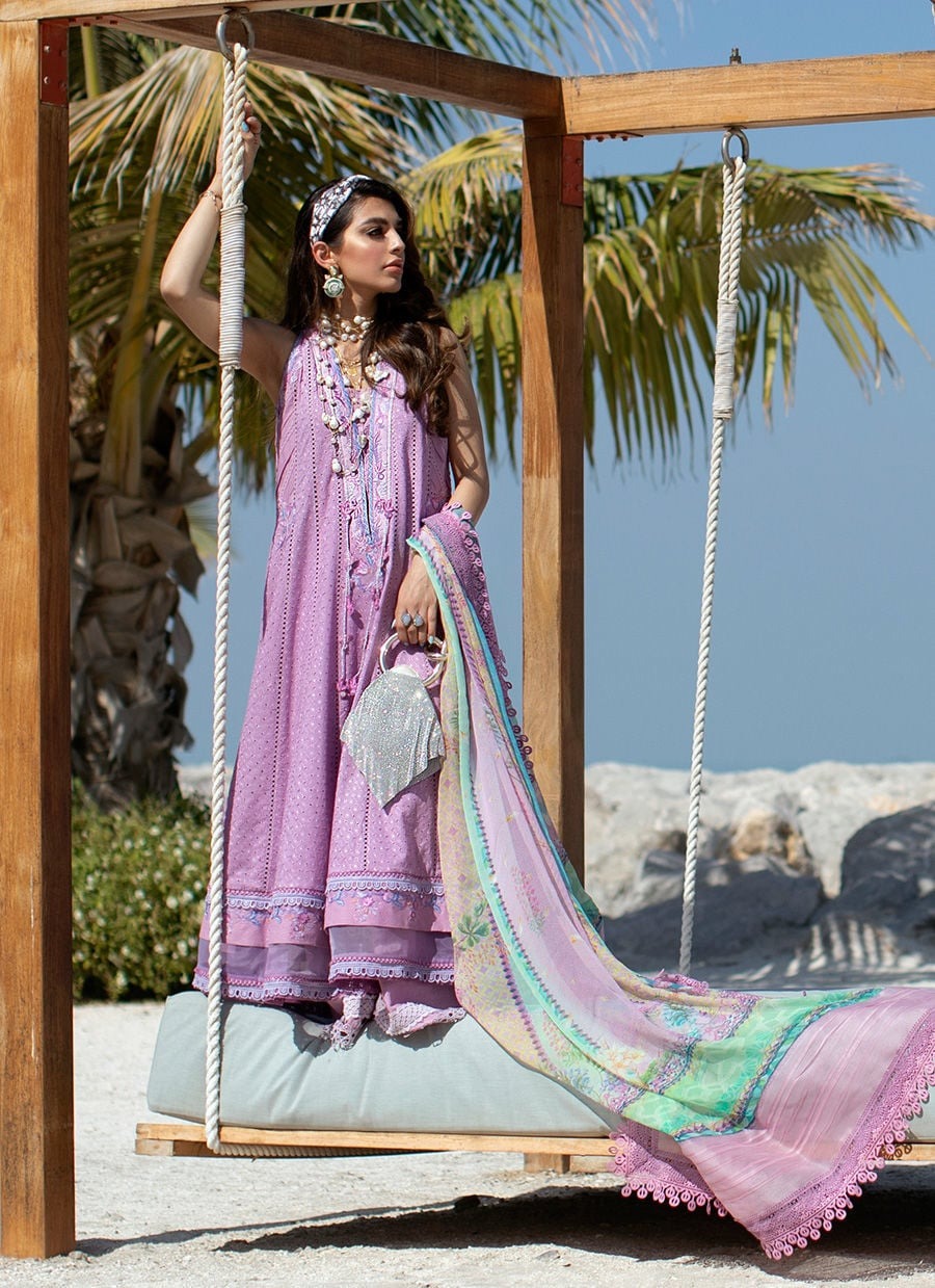 Woman in a pink traditional outfit sitting on a swing with palm trees in the background