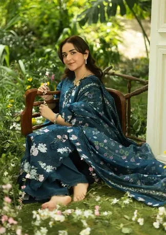 Woman in a blue floral dress sitting on a bench in a garden