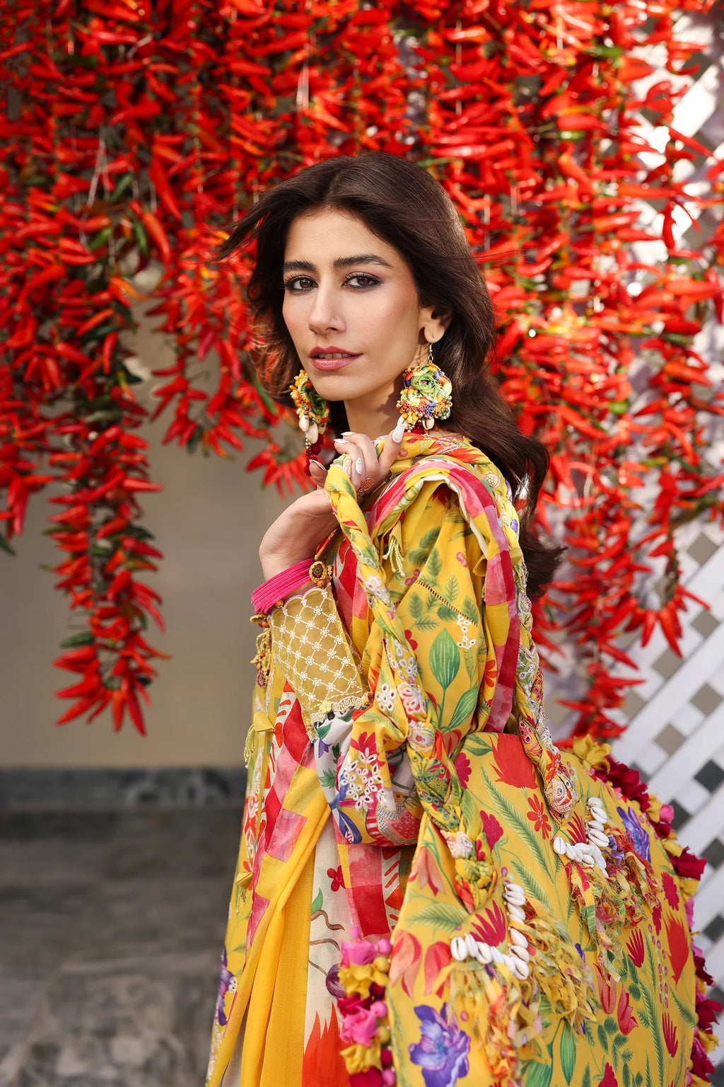 Woman in a colorful floral dress standing in front of red floral decorations