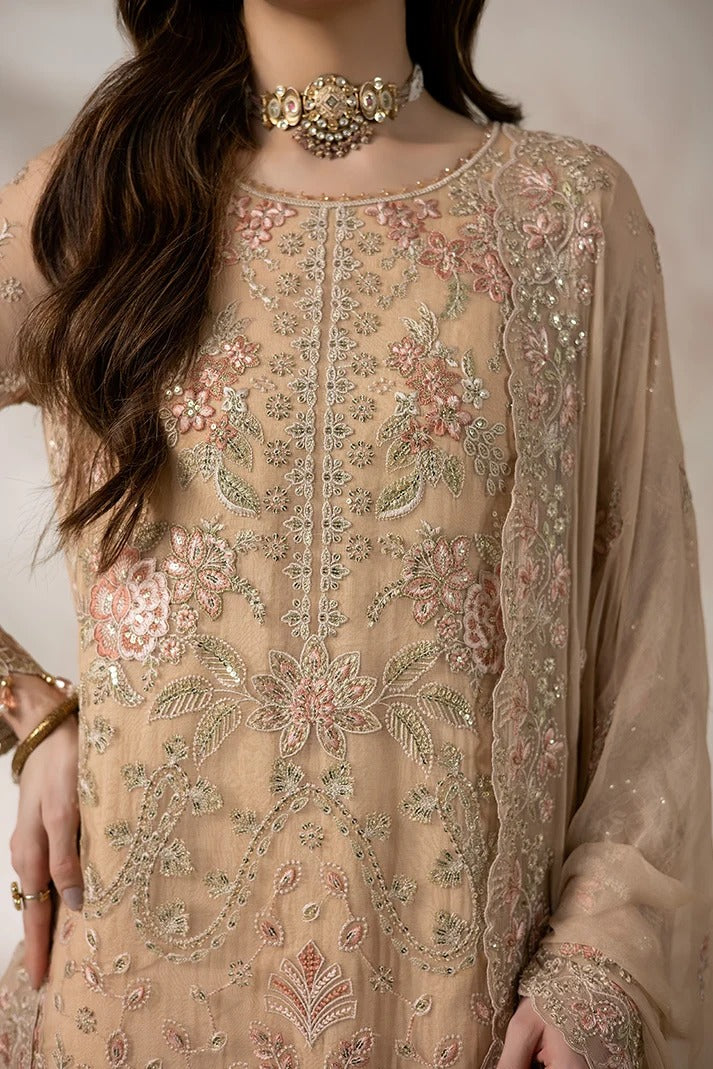 A close-up of a model wearing a beige embroidered traditional outfit with intricate floral patterns in pink, green, and gold, accessorized with a statement necklace.