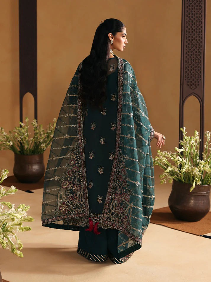 Woman in traditional attire standing in a decorative setting with plants.