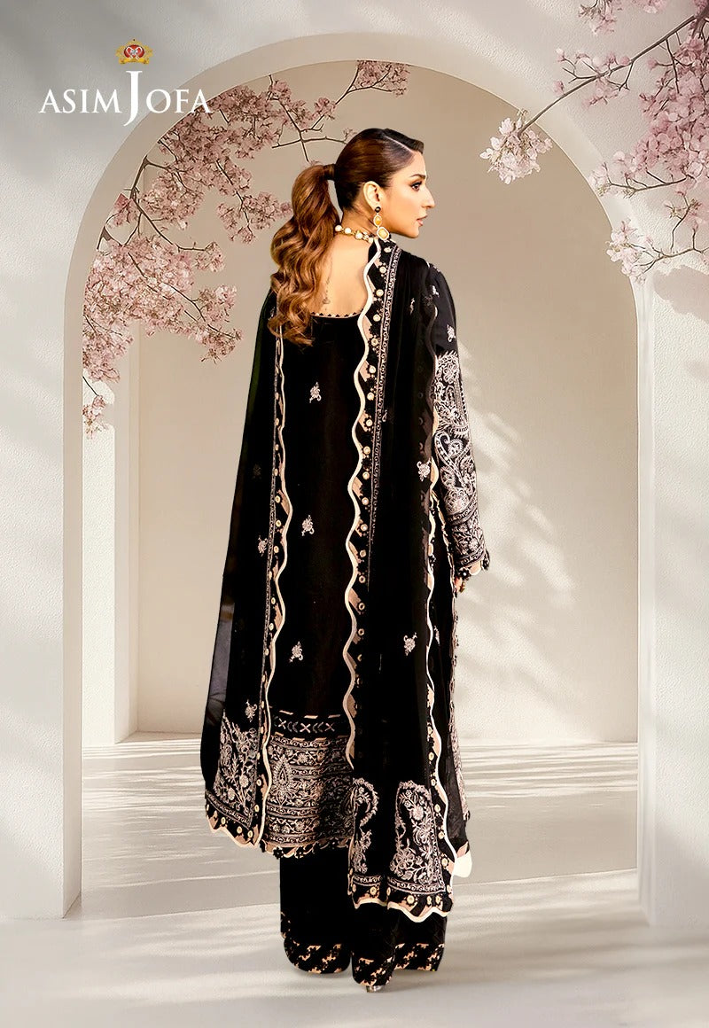 Woman in a black embroidered outfit standing in a decorative archway with cherry blossoms.