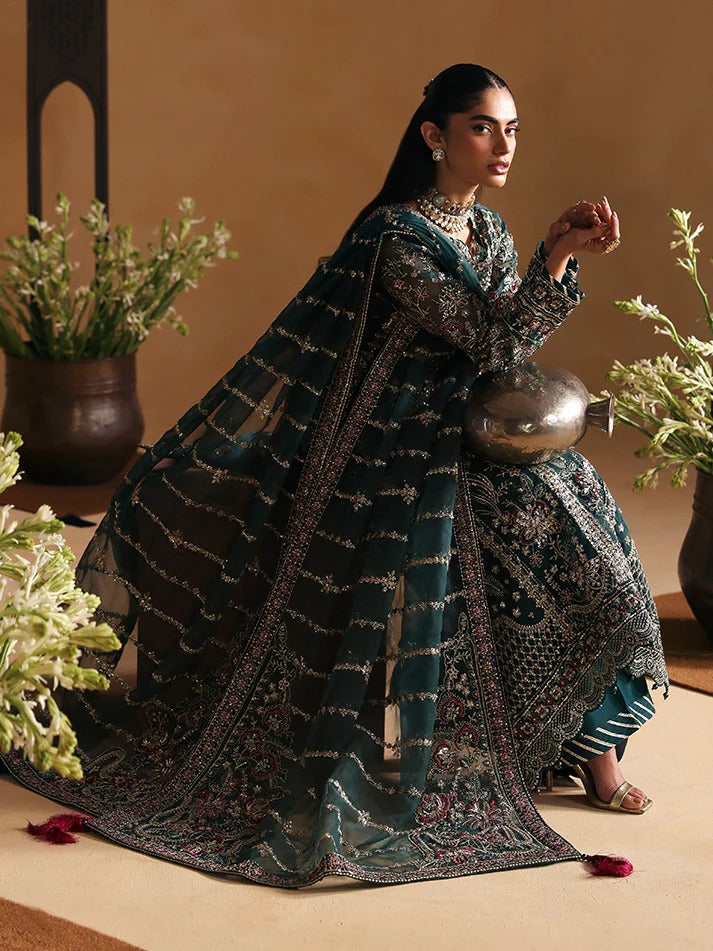 Woman in traditional attire sitting on a decorative stool with plants around.