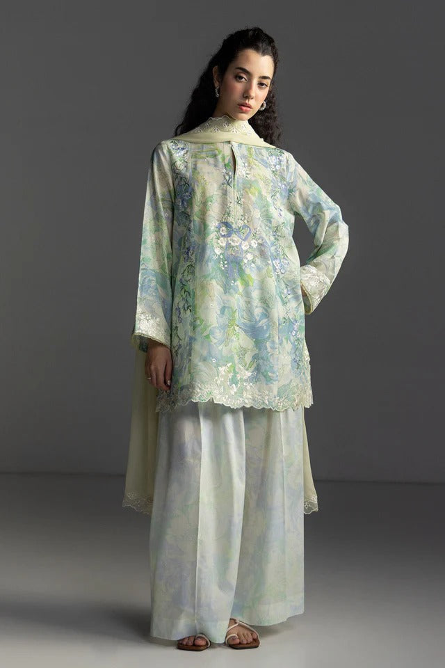 Woman wearing a floral blouse and light-colored pants against a gray background
