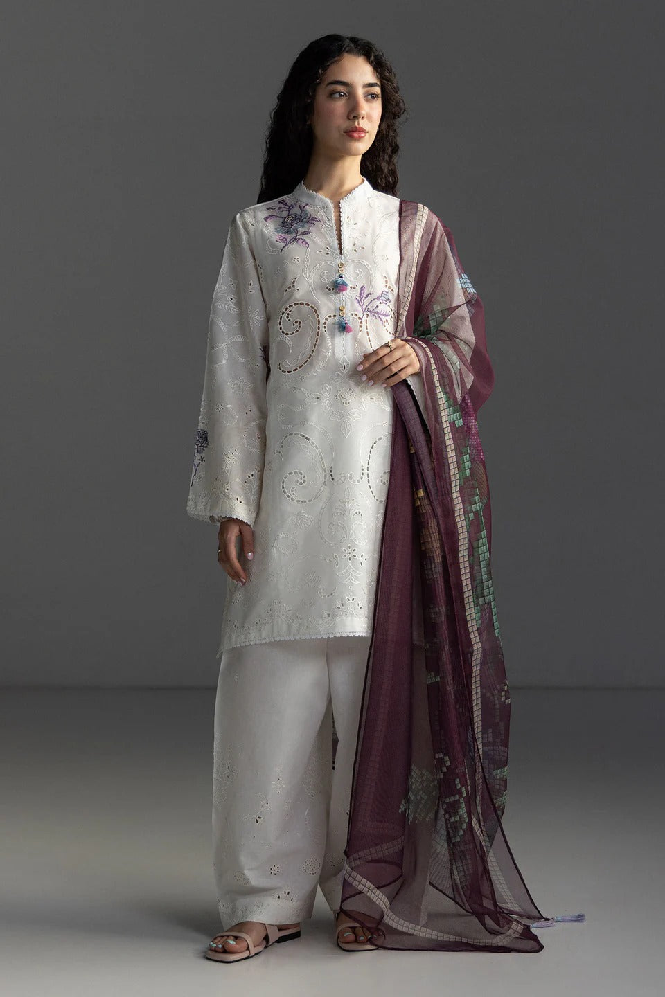 Woman wearing a traditional outfit with a white kurta and white pants, holding a purple dupatta.