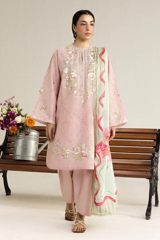 Woman in a pink embroidered outfit with a floral pattern, standing next to a wooden bench with flowers.