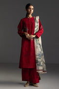 Woman wearing a red traditional outfit with a patterned scarf on a gray background