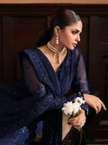 Woman in a blue saree holding flowers indoors