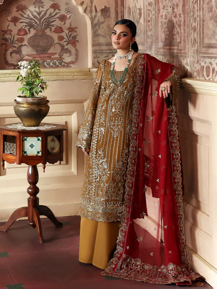 Woman in traditional embroidered outfit with red dupatta in an ornate room.