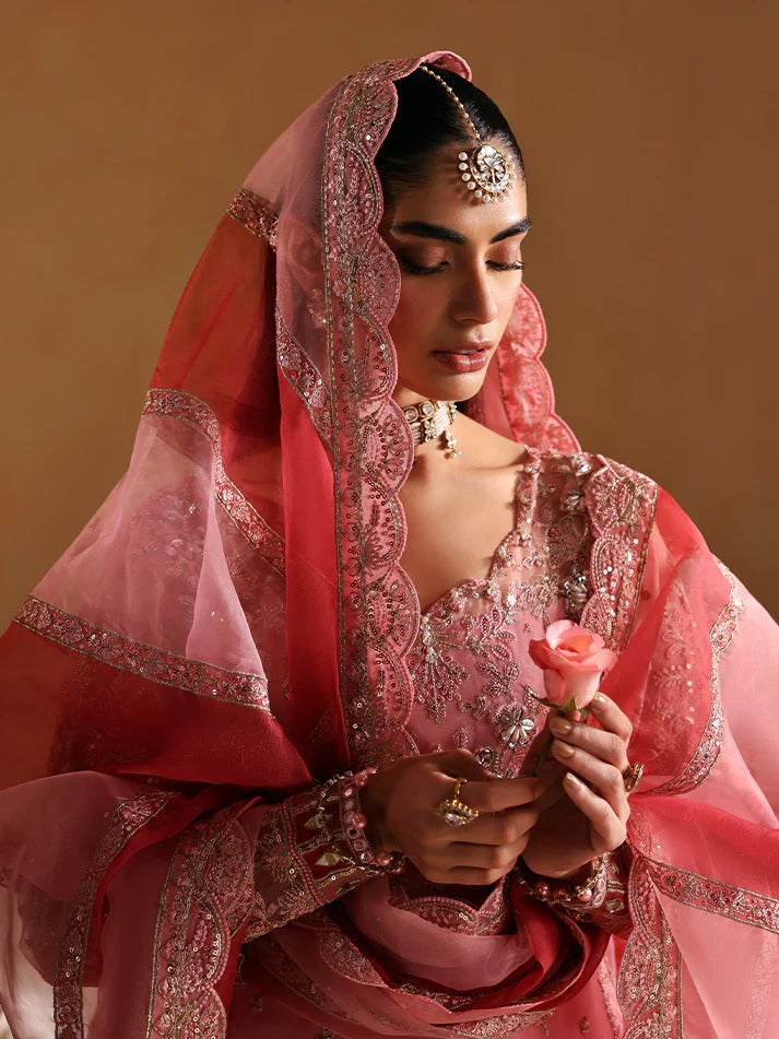 Woman in a pink traditional outfit holding a rose against a beige background