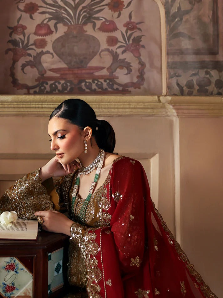 Woman in traditional red and gold outfit sitting in a decorated room.