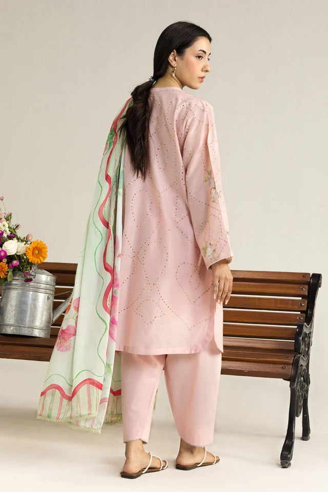 Woman in a pink traditional outfit with a floral dupatta standing next to a wooden bench.