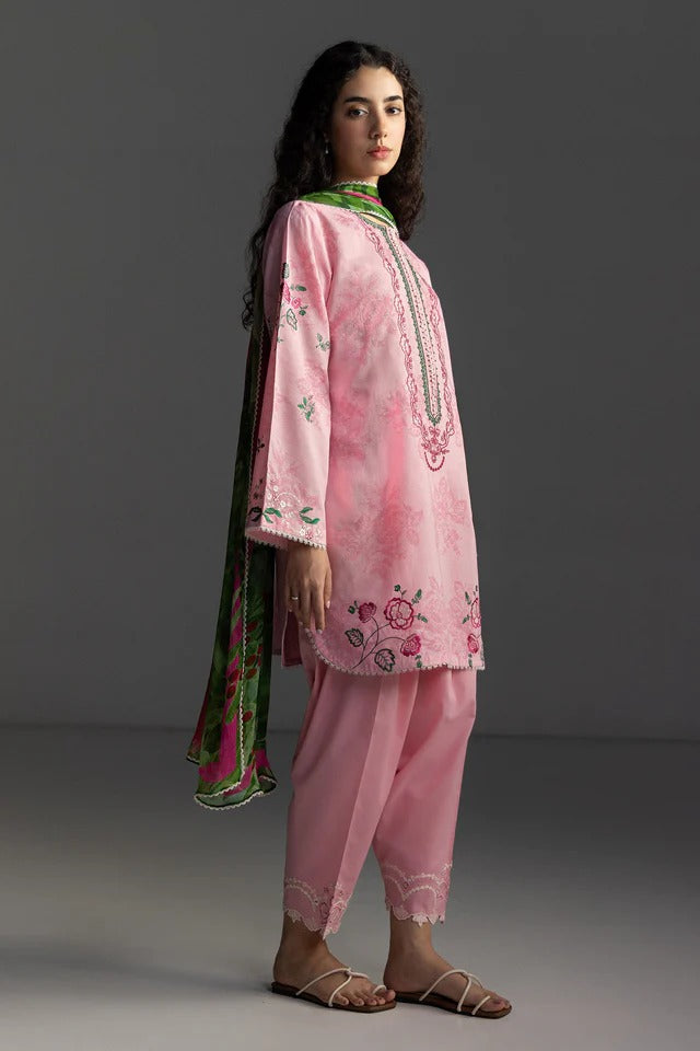 Woman wearing a pink embroidered traditional outfit with a green dupatta on a gray background