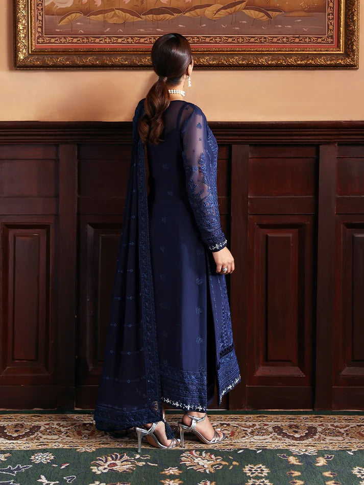Woman in a blue traditional outfit standing in a room with wooden paneling and a large painting.