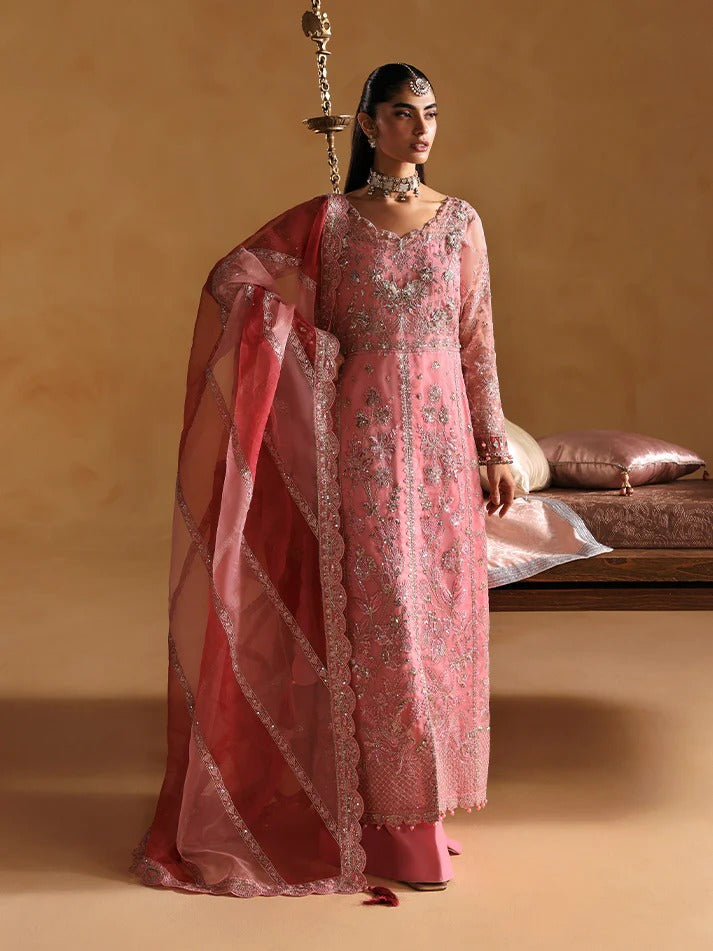 Woman in a pink traditional outfit with a matching dupatta against a beige background