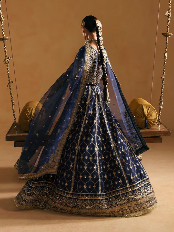Woman in a traditional blue embroidered outfit standing on a swing with a beige background