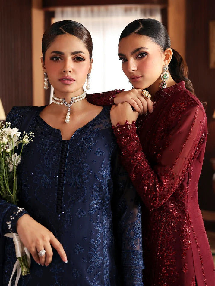 Two women in elegant dresses posing together indoors.