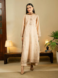 A woman modeling a long beige embroidered kurta with matching trousers and a dupatta in a warm, decorated indoor setting.