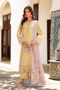 Woman in a light yellow traditional outfit with a floral design in an outdoor setting.