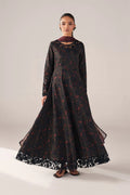 Woman wearing a long black dress with floral patterns on a plain background