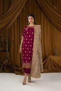 A woman models a traditional Indian salwar kameez suit in deep magenta with gold embroidery, paired with a beige printed dupatta, set against a draped brown velvet backdrop.