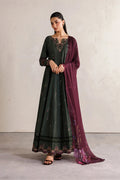 A woman models a dark green embroidered Anarkali gown with a deep purple dupatta draped over one shoulder, set against a neutral textured wall.