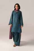 Woman wearing a teal embroidered outfit with a plain background