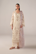 Woman wearing a long, light-colored floral dress against a plain background