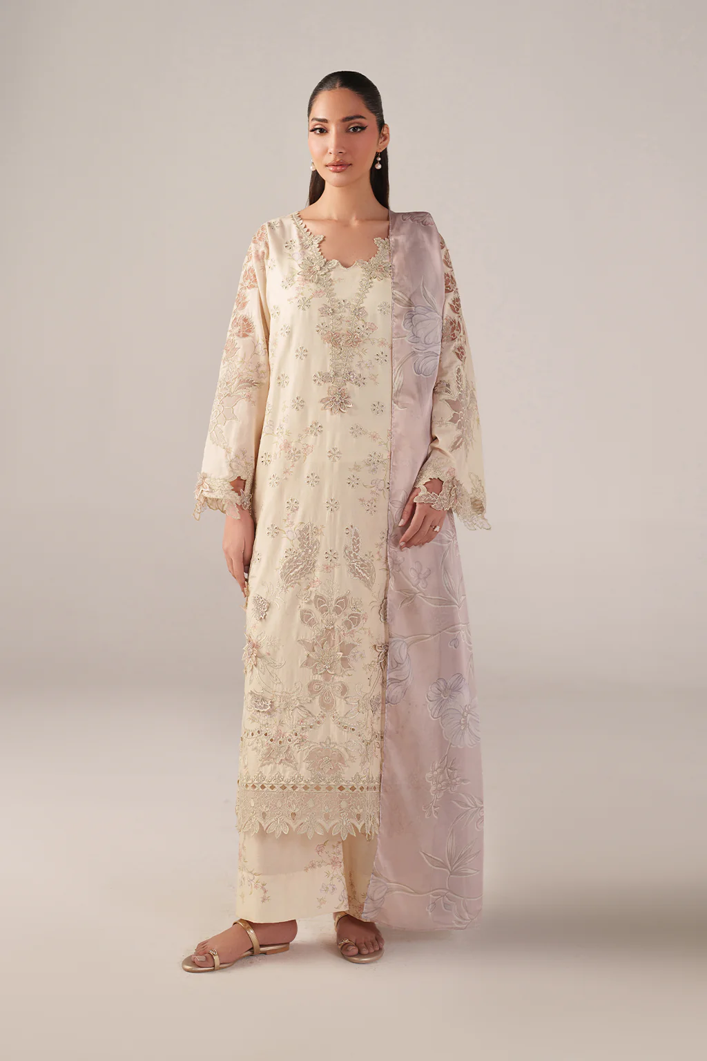 Woman wearing a long, light-colored floral dress against a plain background