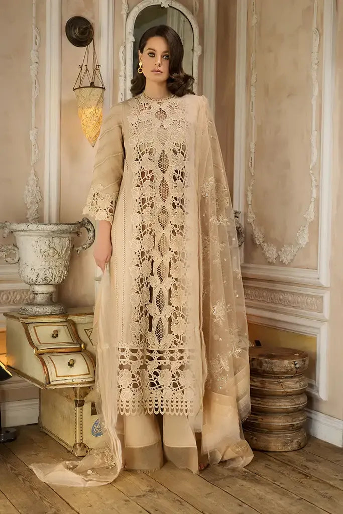 Woman in a beige embroidered outfit standing in an elegant interior setting.