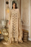 Woman in a beige embroidered outfit standing in an elegant interior setting.