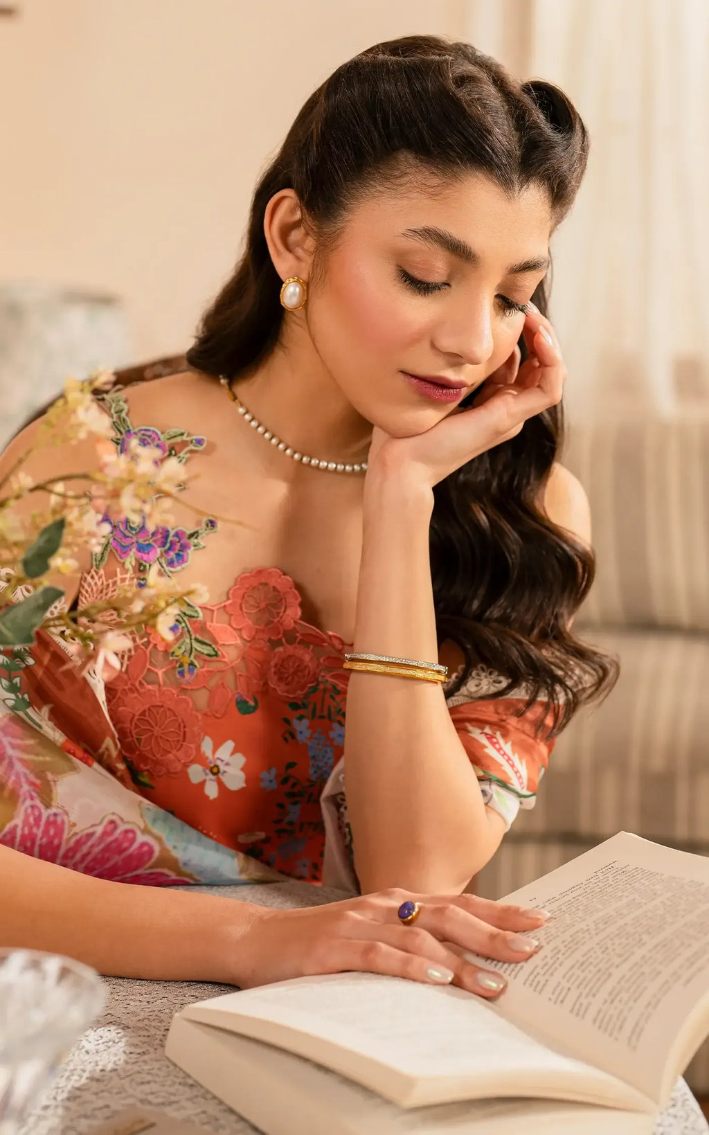 Woman in a floral dress reading a book with a soft focus background
