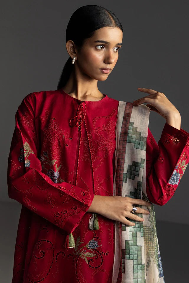Woman wearing a red embroidered outfit with a patterned scarf against a dark background