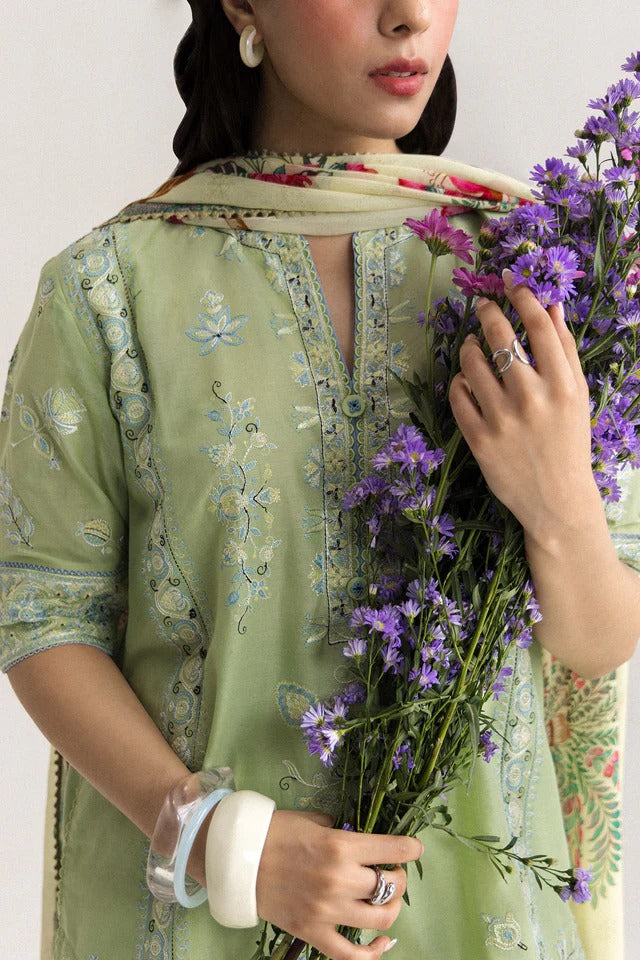 Woman holding a bouquet of purple flowers wearing a green embroidered outfit.