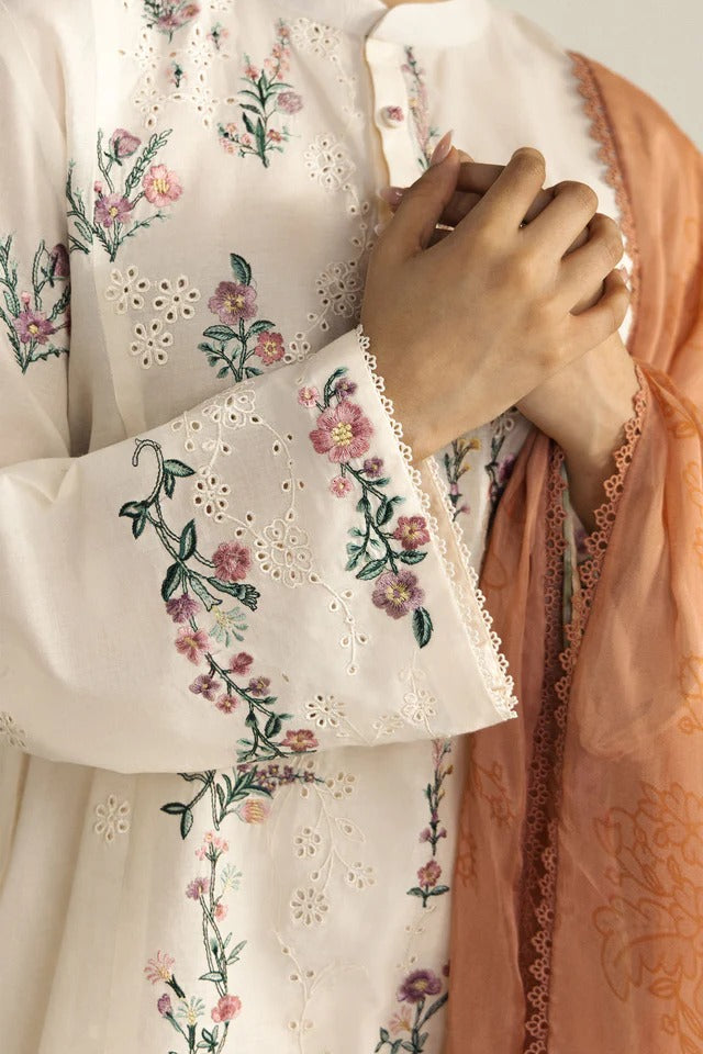 Close-up of a garment with floral embroidery and a peach-colored fabric.