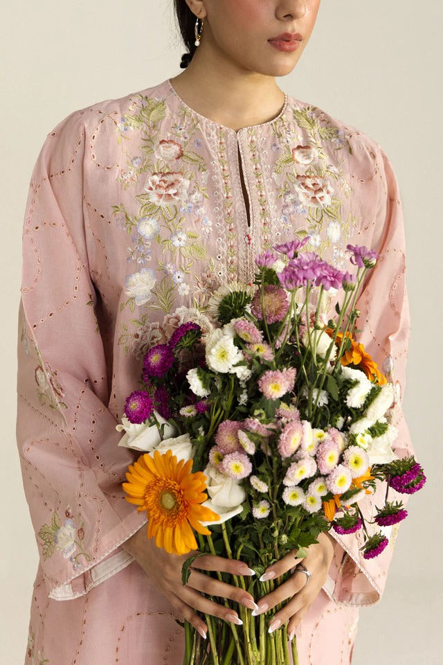 Person wearing a floral dress holding a bouquet of flowers against a neutral background