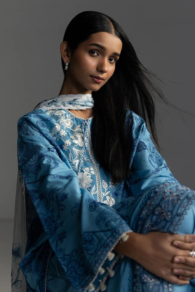 Woman wearing a blue embroidered traditional outfit against a gray background