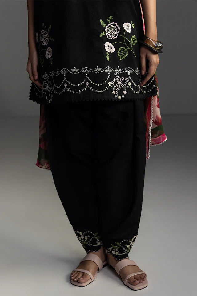 Person wearing a black outfit with floral embroidery on a gray background