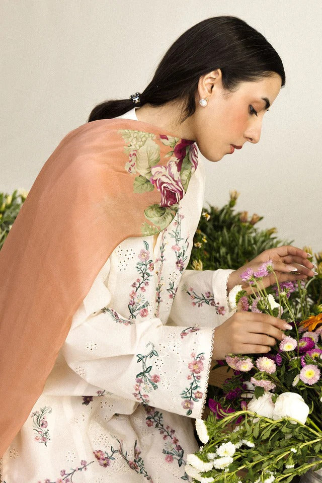 Woman in a floral dress arranging flowers against a neutral background