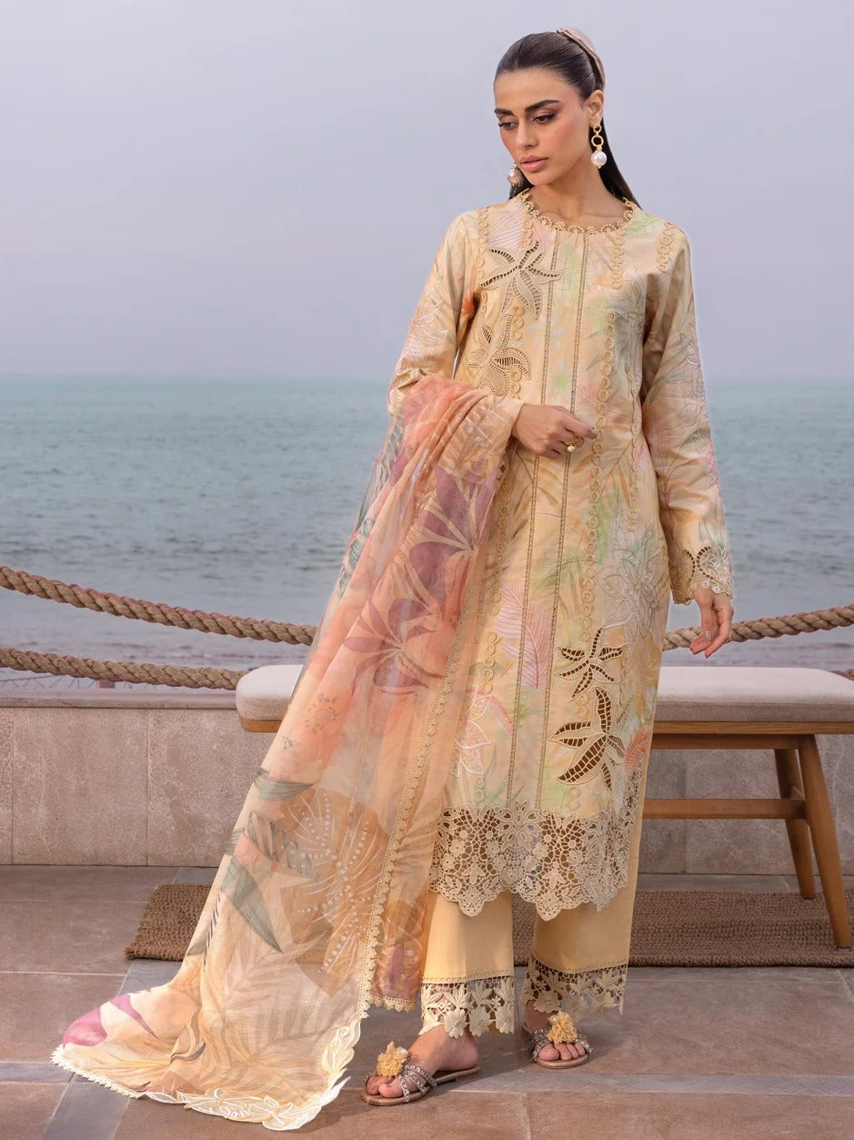 Woman in a beige and floral outfit standing by the ocean.