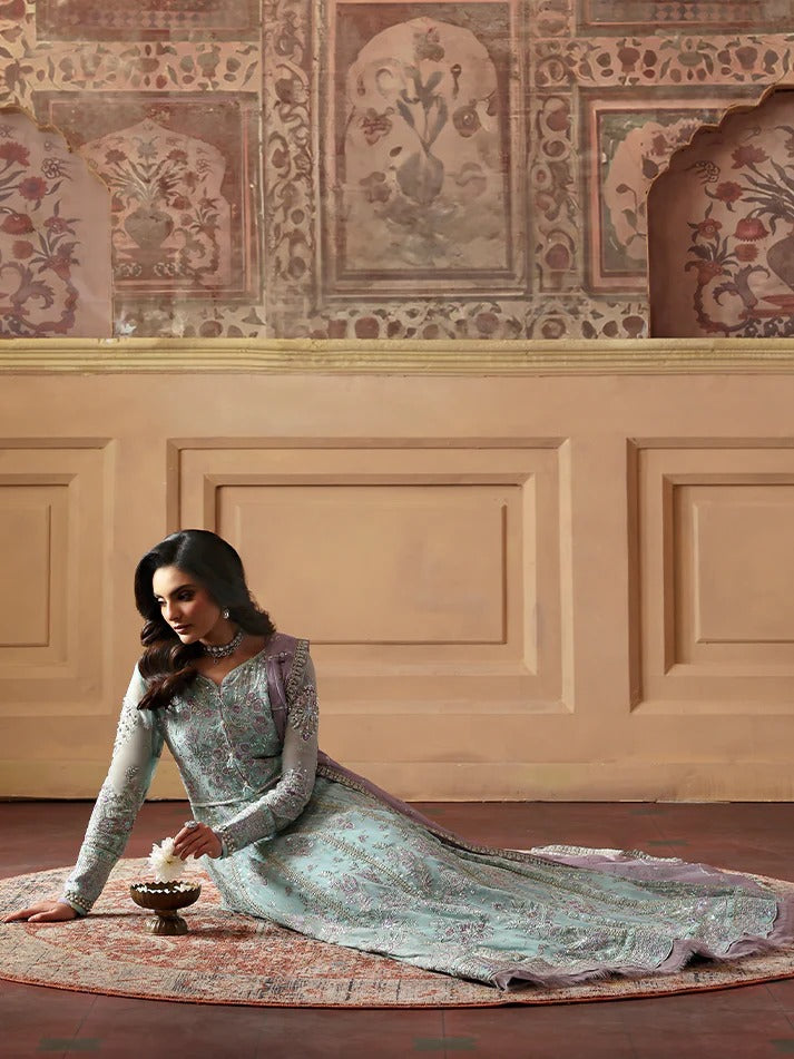Woman in a traditional outfit sitting on a rug in a decorated room.