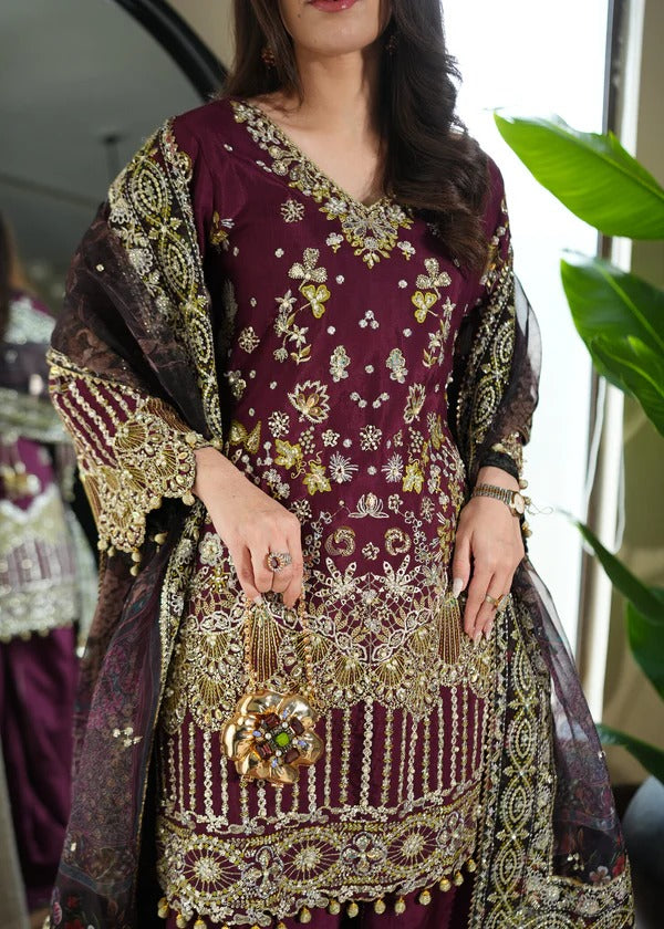 Woman wearing a maroon and gold embroidered traditional outfit with a matching shawl.