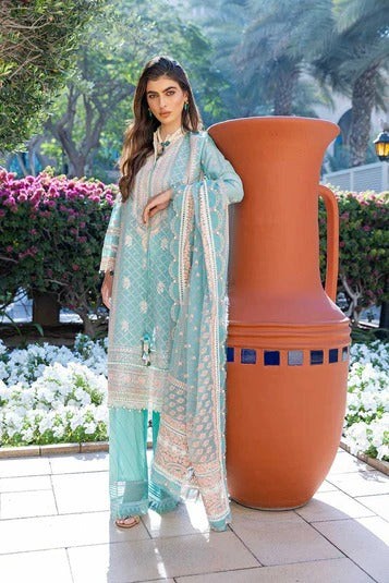 Woman in a light blue traditional outfit standing next to a large decorative vase outdoors.
