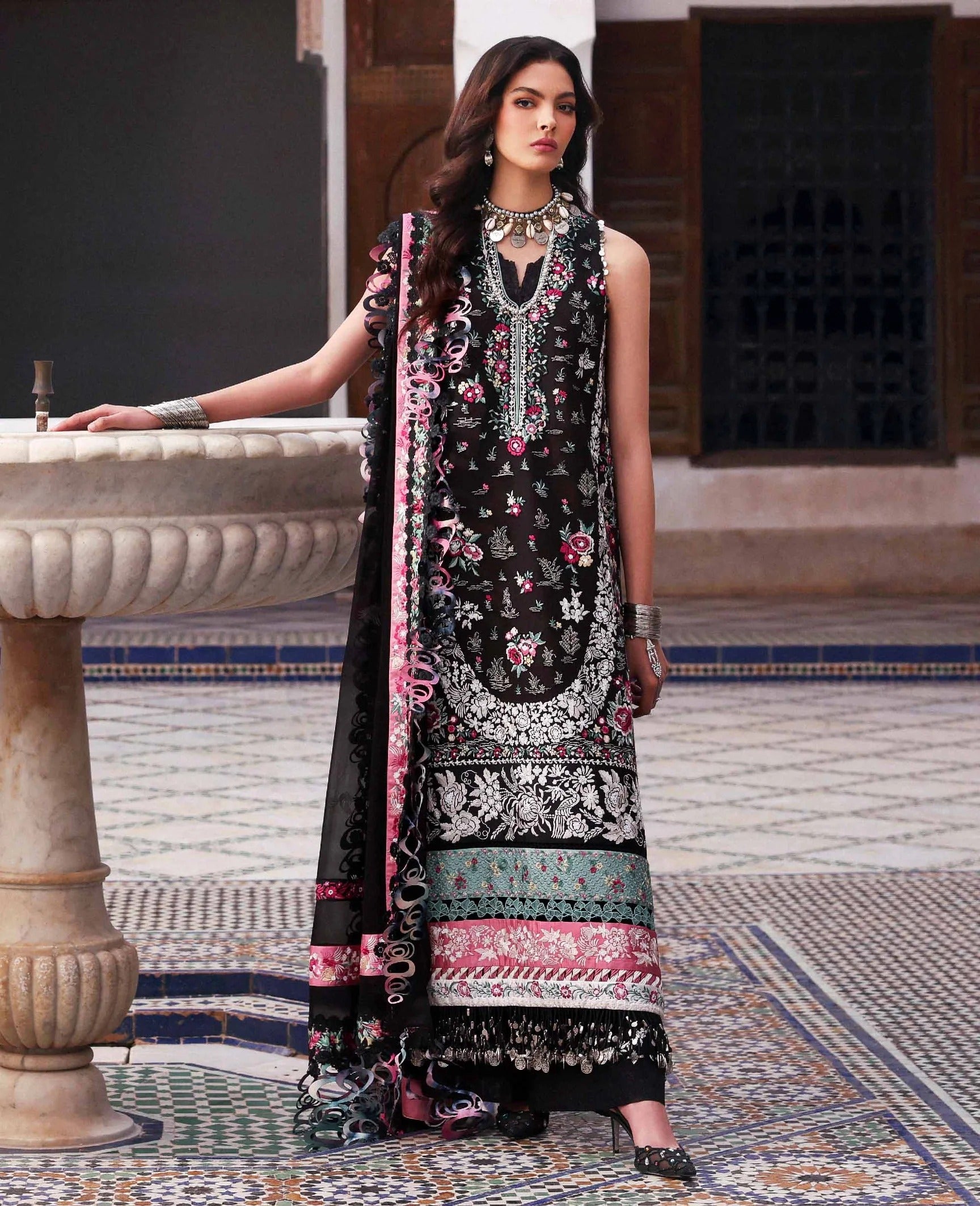 Woman in a black floral dress standing in a decorative courtyard.