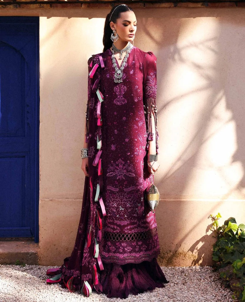Woman in a traditional purple embroidered outfit standing against a beige wall with a blue door.