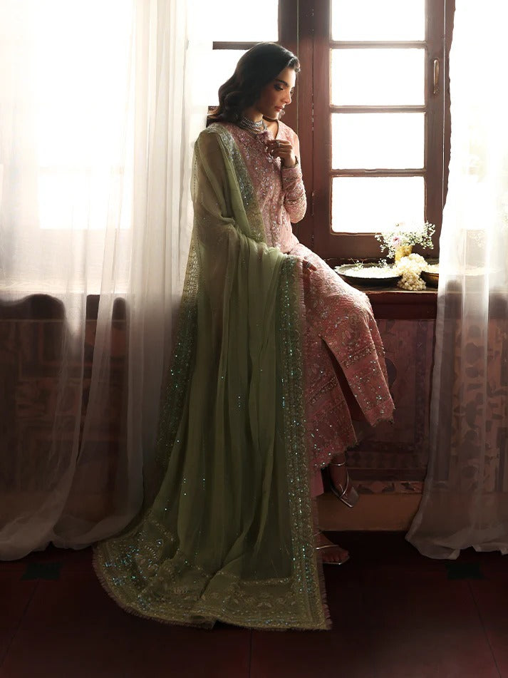 Woman in a traditional outfit sitting by a window with light streaming in