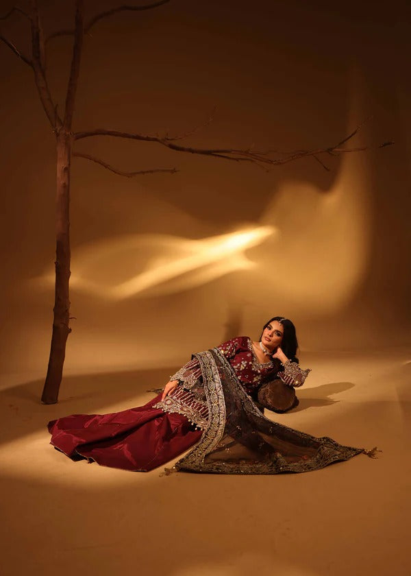 Woman in a red and gold traditional outfit sitting under a tree with warm lighting.